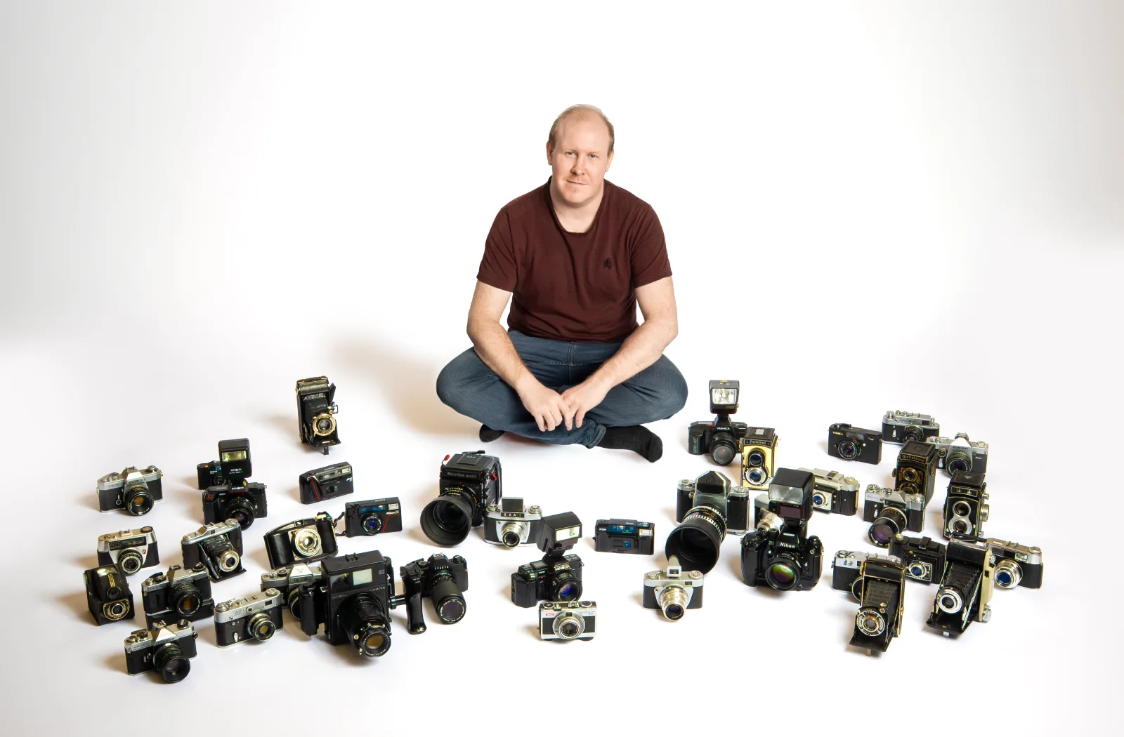Aaron Roberts, photographer in Cluj-Napoca, sitting among his collection of cameras